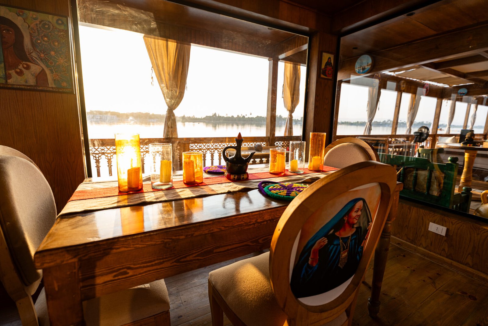 NR-ES dahabiya Nile-facing dining detail with warm light and boutique interior atmosphere