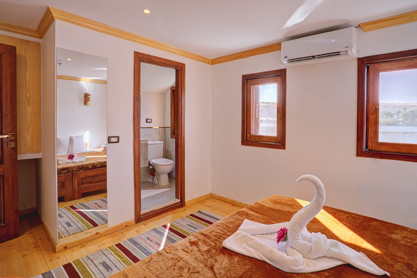 NR-KD dahabiya cabin with bed, air conditioning, bathroom access, and Nile-facing windows