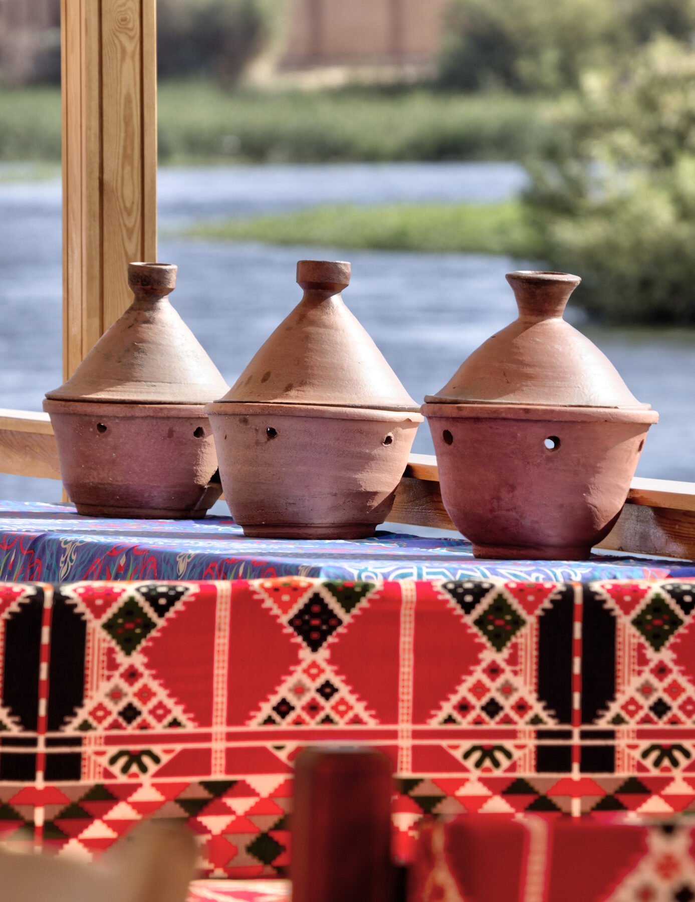 NR-KD dahabiya Nubian dining detail with clay pots, colorful textiles, and Nile view