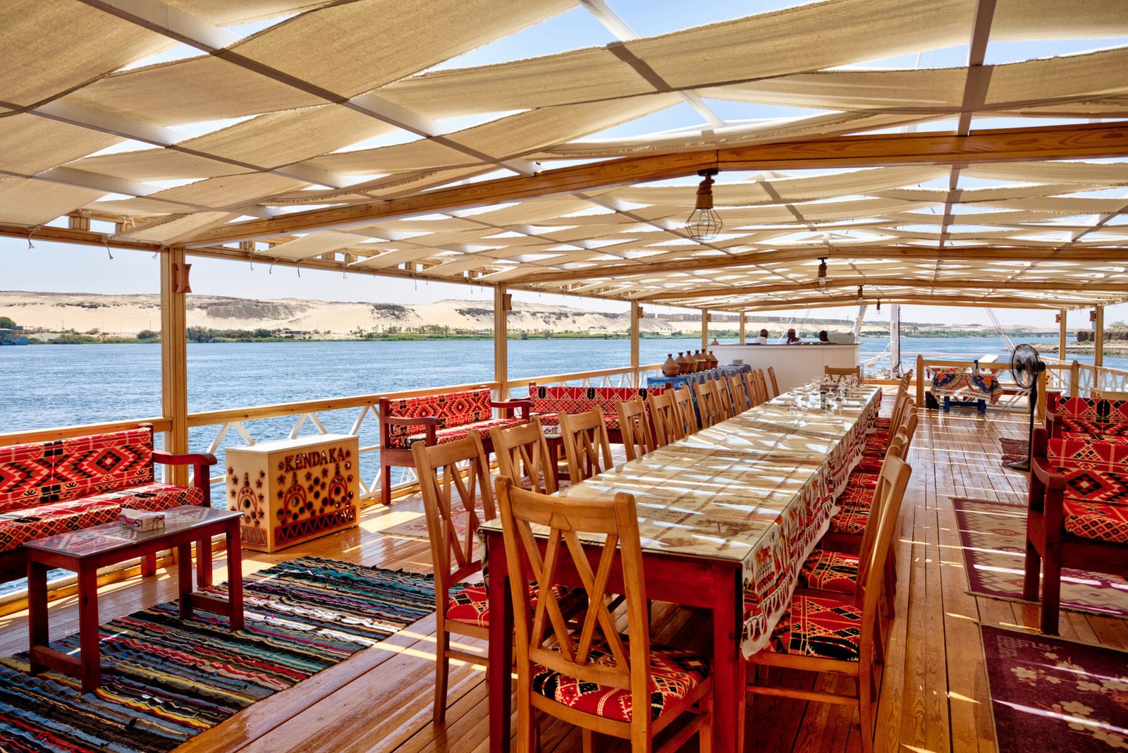 NR-KD dahabiya open deck with dining table, shaded seating, and Nile view