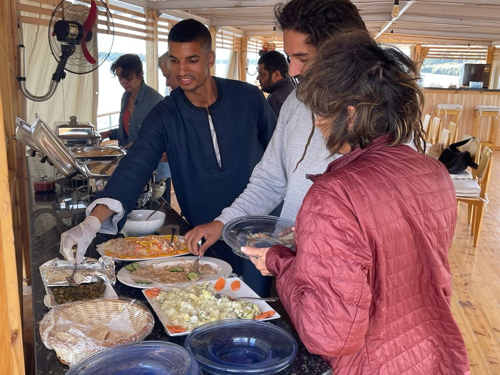 NR-SF dahabiya hosted dining moment with guests and onboard service during a private Nile journey