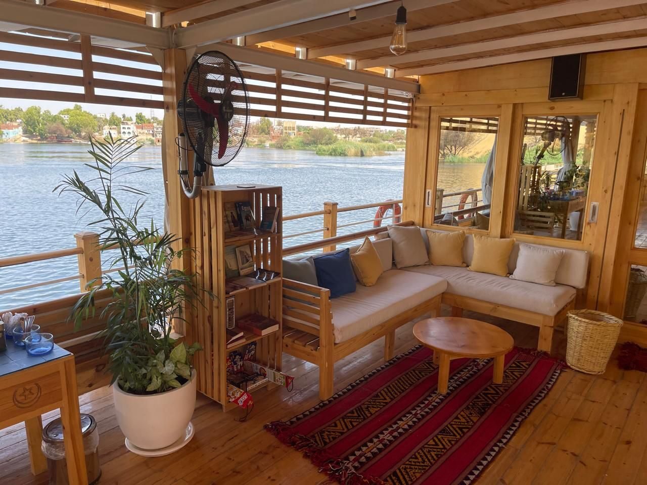 NR-SF dahabiya Nile-facing lounge with warm wooden interior and calm onboard rhythm